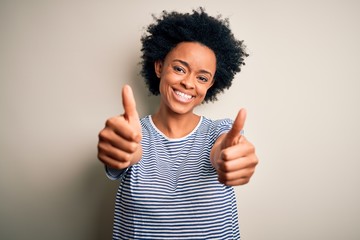 Young beautiful African American afro woman with curly hair wearing striped t-shirt approving doing...