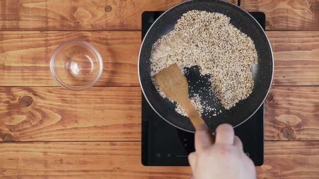 Frying sesame in the pan and stirring with wooden spoon. Fix cam.
