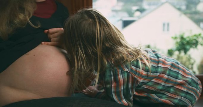 Little toddler looking at his pregnant mother's belly