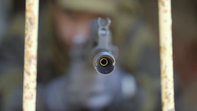 A soldier approaches with a rifle and points the barrel directly at the camera. Close-up point of view.