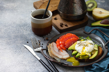 Valentine's day breakfast. Boiled egg sandwich with avocado, coffee, salmon and smoked salmon on a stone concrete tabletop. Copy space.