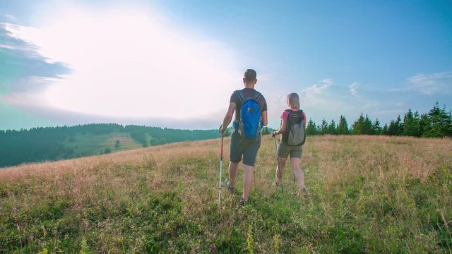 Slow motion shot of two attractive hikers getting to the top of a hill and admiring the landscape