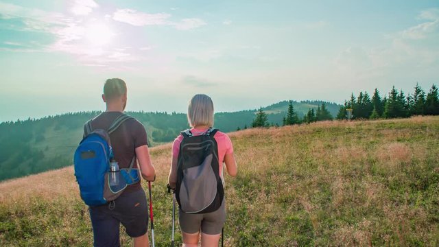 Slow motion of a couple of hikers talking while walking on the top of a hill