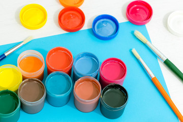 Colorful school paints.  Blue background, brushes