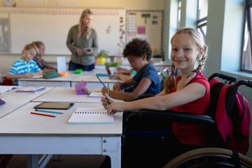 Schoolgirl sitting in a wheelchair in an elementary school classroom