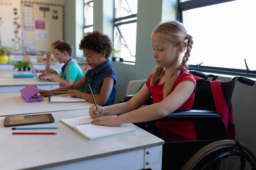 Schoolgirl sitting in a wheelchair in an elementary school classroom
