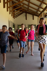 Group of schoolchildren running in an outdoor corridor at elementary school