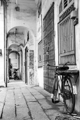 Zwart-wit foto van retro fiets in een smal steegje, oude stad