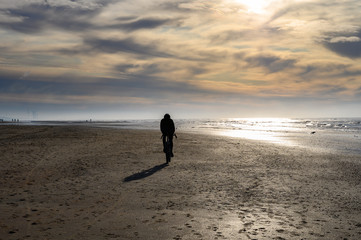 Unidentified man riding on sport bicycle on North sea sandy beach during low tide near Castricum aan Zee, Netherlands