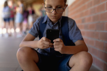 Schoolboy sitting on a step in the schoolyard at elementary school 
