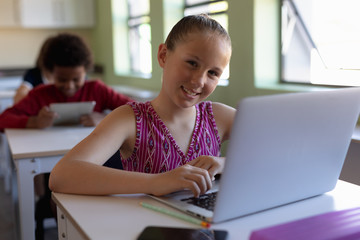 Schoolgirl sitting at a desk using a laptop computer