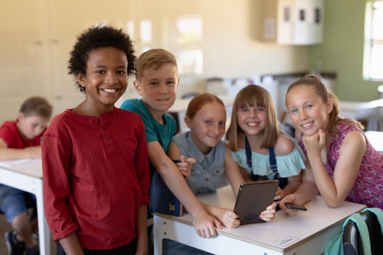 Group of schoolchildren around a desk using a tablet computer