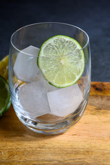 Glass with ice cubes and green lime