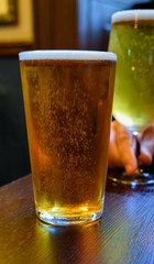 Misty glasses with two pints of cold Scotch ale, amber pale ale, lager draft beer in English pub