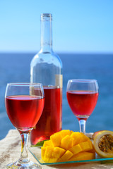 Two glasses with rose wine served outdoor with exotic fruits on tropical island La Palma, Canary islands, Spain with beautiful blue ocean view