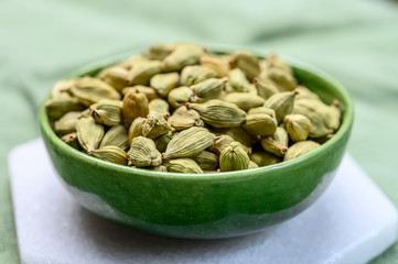 Green pods of cardamom spice in green bowl