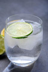  Cold drinking mineral water served in glass with ice cubes and green lime