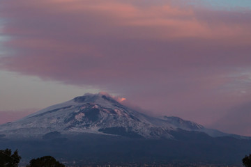A beautiful view of the eruption of volcano Etna with smoke and snow is in the photo in winter in Sicily