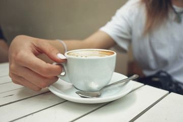Abstract soft focus woman holding cup of hot coffee on wood table