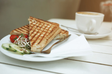 Club sandwich with cheese and cherry tomato on white wooden table.