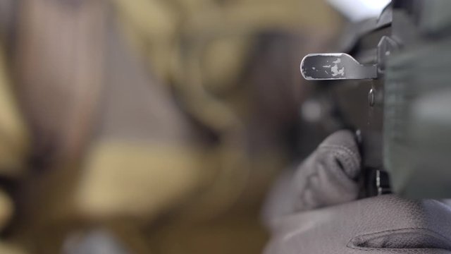 Close-up of looking along the side of A kalashnikov rifle assault rifle as a soldier charges the weapon.