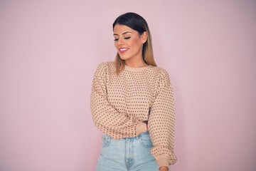 Fototapeta premium Young beautiful woman wearing fashionable clothes smiling happy and confident. Standing with smile on face over isolated pink background