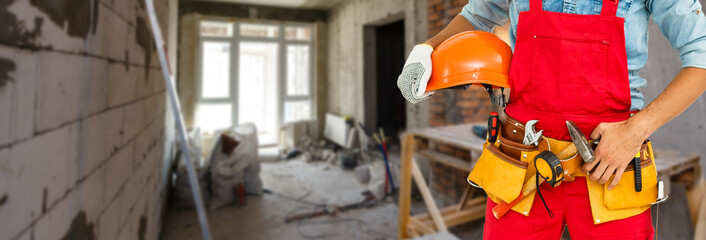 Construction worker at construction site with protective uniform, construction service tools and...