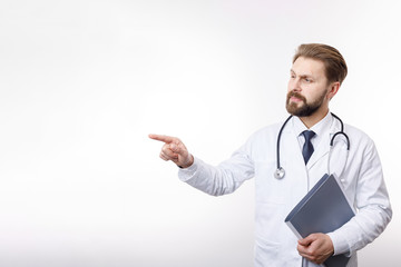 Intelligent physician in white smock and shirt pointing at something isolated white background copyspace