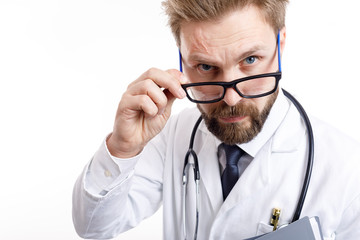 Fototapeta premium Close-up of young bearded doctor with stethoscope looking at camera over glasses isolated white background
