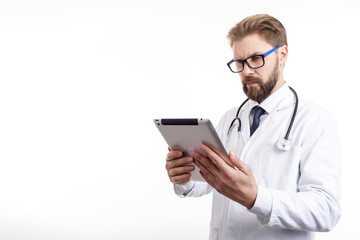 Thoughtful male doctor with beard and glasses checking information via tablet isolated white background copyspace