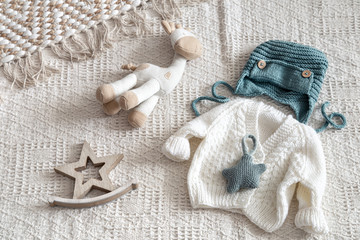 Knitted children's clothing on a light background with accessories