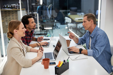 Creative team using laptops and communicating in office