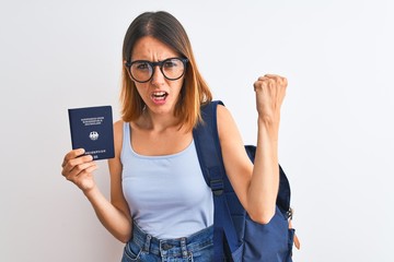Beautiful redhead student woman wearing backpack and holding passport of germany annoyed and frustrated shouting with anger, crazy and yelling with raised hand, anger concept