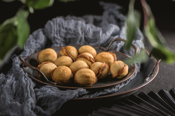Homemade cookies shaped nuts with cream boiled condensed milk on dark background