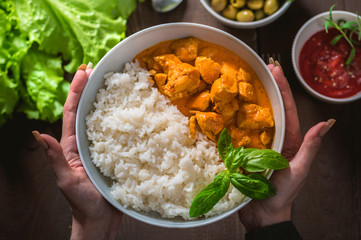 Indian curry chicken with basmati rice in bowl with spices and herbs