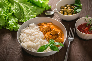 Indian curry chicken with basmati rice in bowl with spices and herbs