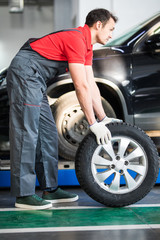 Obraz na płótnie Canvas Auto mechanic carrying tire in tire store