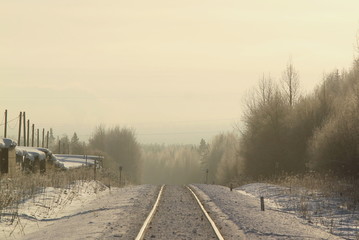 Railroad stretching into the distance a winter sunny day between the city and the forest
