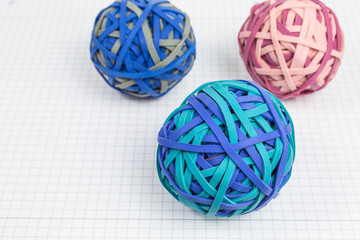 balls of rubber bands in blue, green, pink and gray