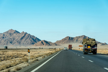 Road view with private cars and trucks between Kerman and Yazd, Iran