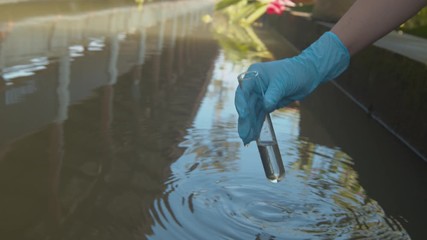 Collecting a water sample in a test tube to check for pollution, contamination, ph, acid, alkaline levels in the local water supply