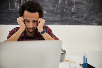 Annoyed young man working laptop in office