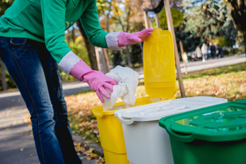 Volunteer girl sorts garbage in the street of the park. Concept of recycling. 