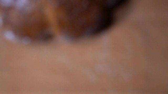 Flower shaped fennel seed bread with golden baked crust falling down on wooden chopping board while going out of focus, SLOW MOTION.