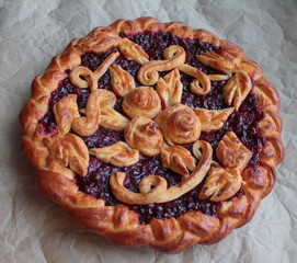 Delicious golden round pie with red cherry and lingonberry filling with dough pattern
