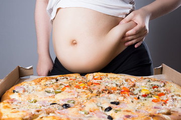 Fat woman with a piece of pizza, unhealthy nutrition concept