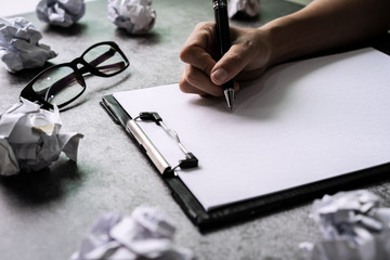 Hand writing on file folder with crumpled paper balls on desk office, Creativity problems concept