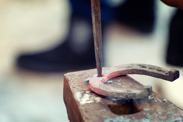 Blacksmith working metal with hammer on the anvil