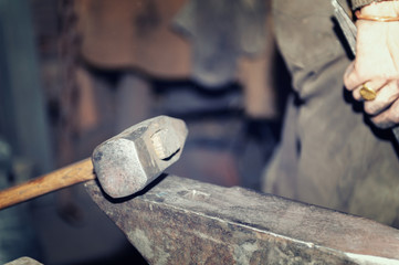 Blacksmith working metal with hammer on the anvil