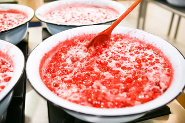 Strawberry jam cooking process. Wooden spoonmixing jam. Organic traditional jam manufacturing.